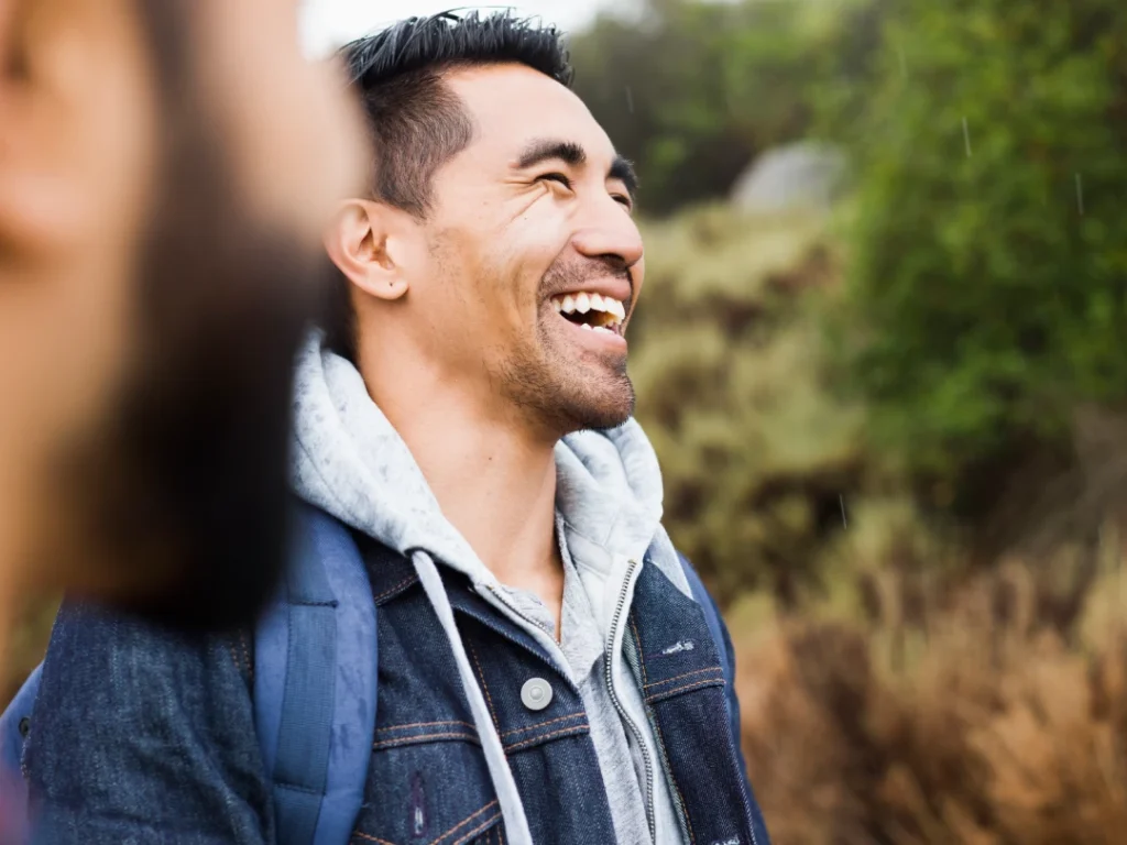 The Grove Recovery | man laughing outside wearing jean jacket and backp